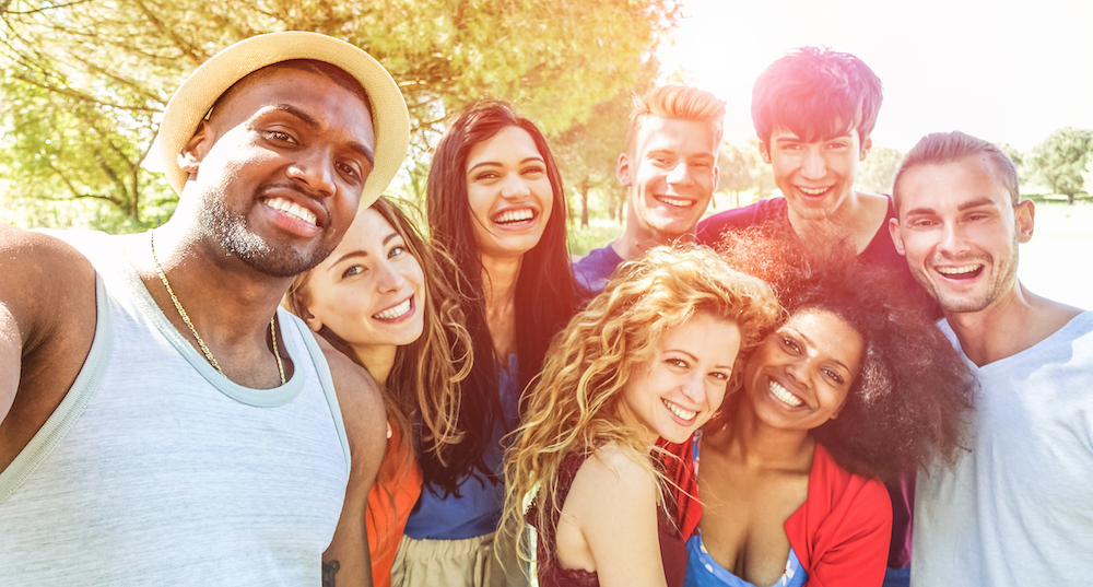 Happy friends taking selfie at bbq picnic in nature park with back sunlight